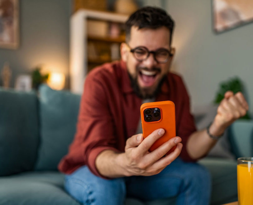 Smiling men celebrating while using his phone